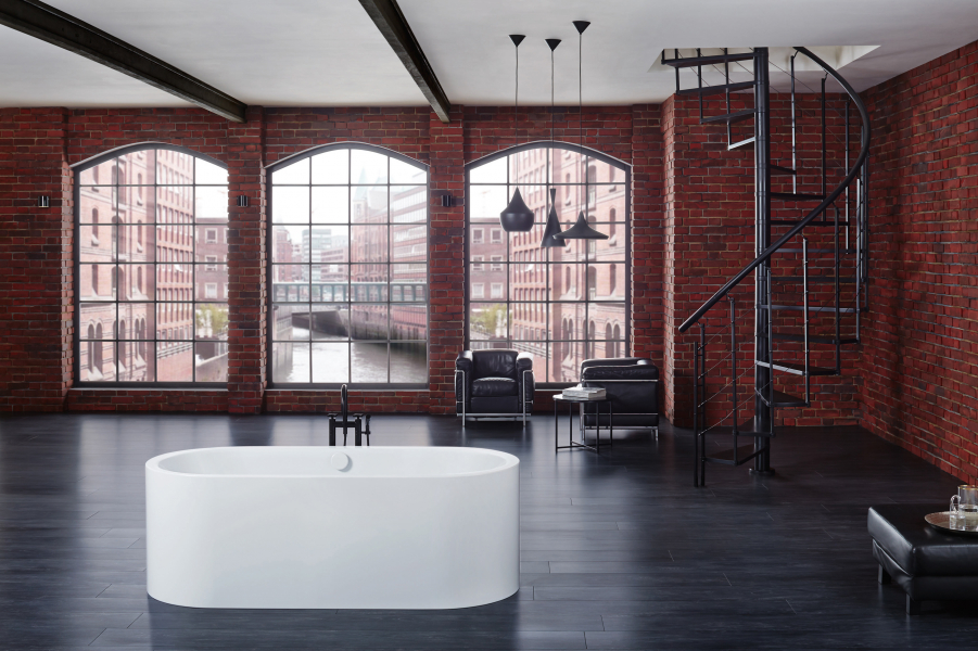 Moderne Badewanne vor Backsteinwand mit Loftfenstern und Wendeltreppe