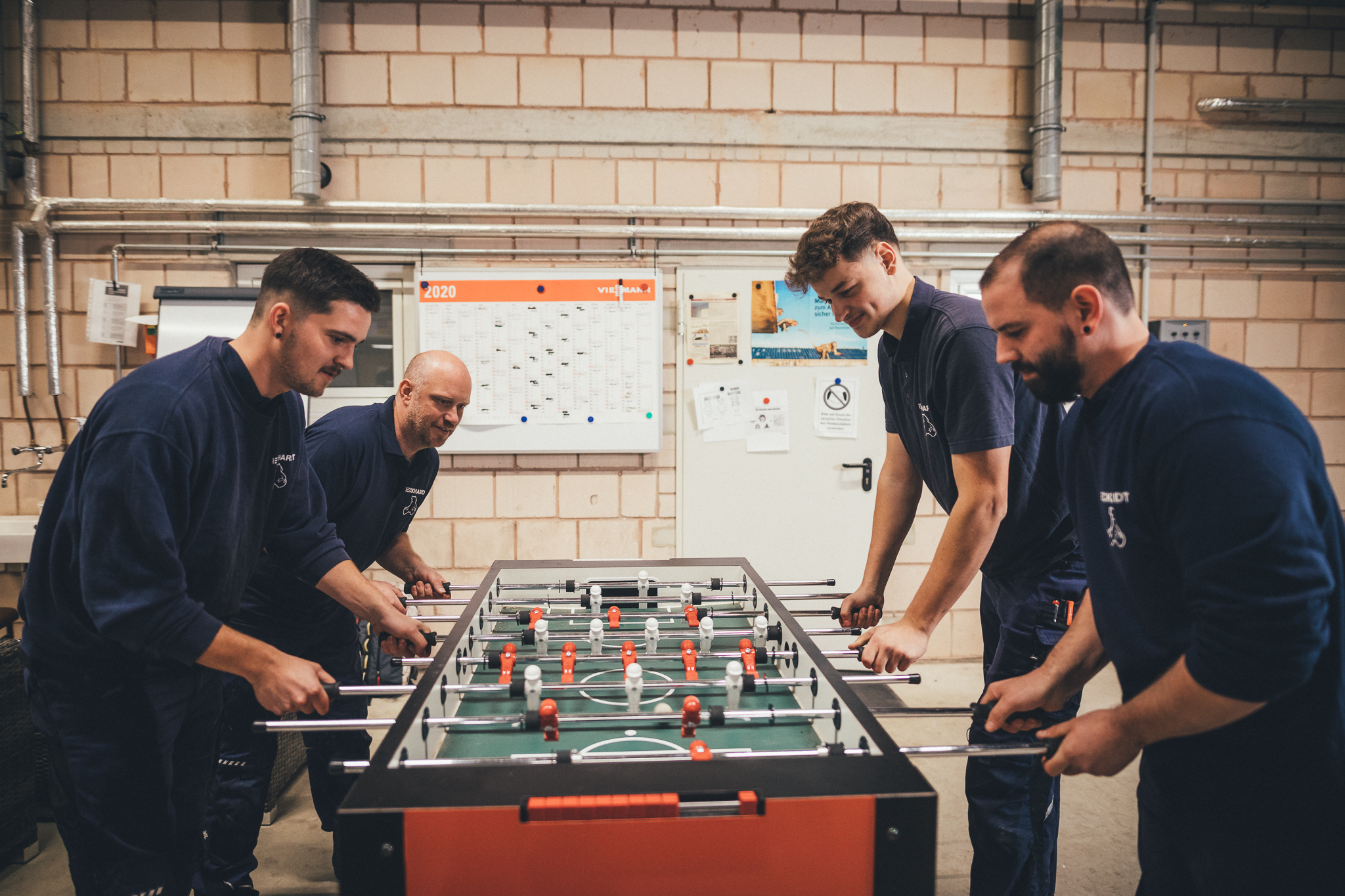 Vier Männer spielen Tischkicker in Werkhalle