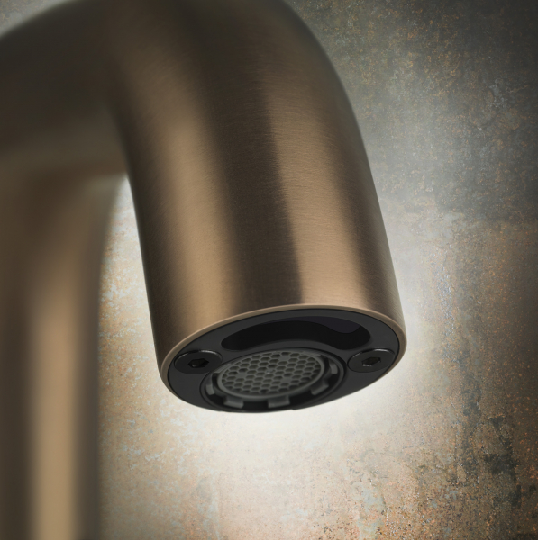 Detailaufnahme eines bronze-matten Wasserhahns vor strukturierter Wand