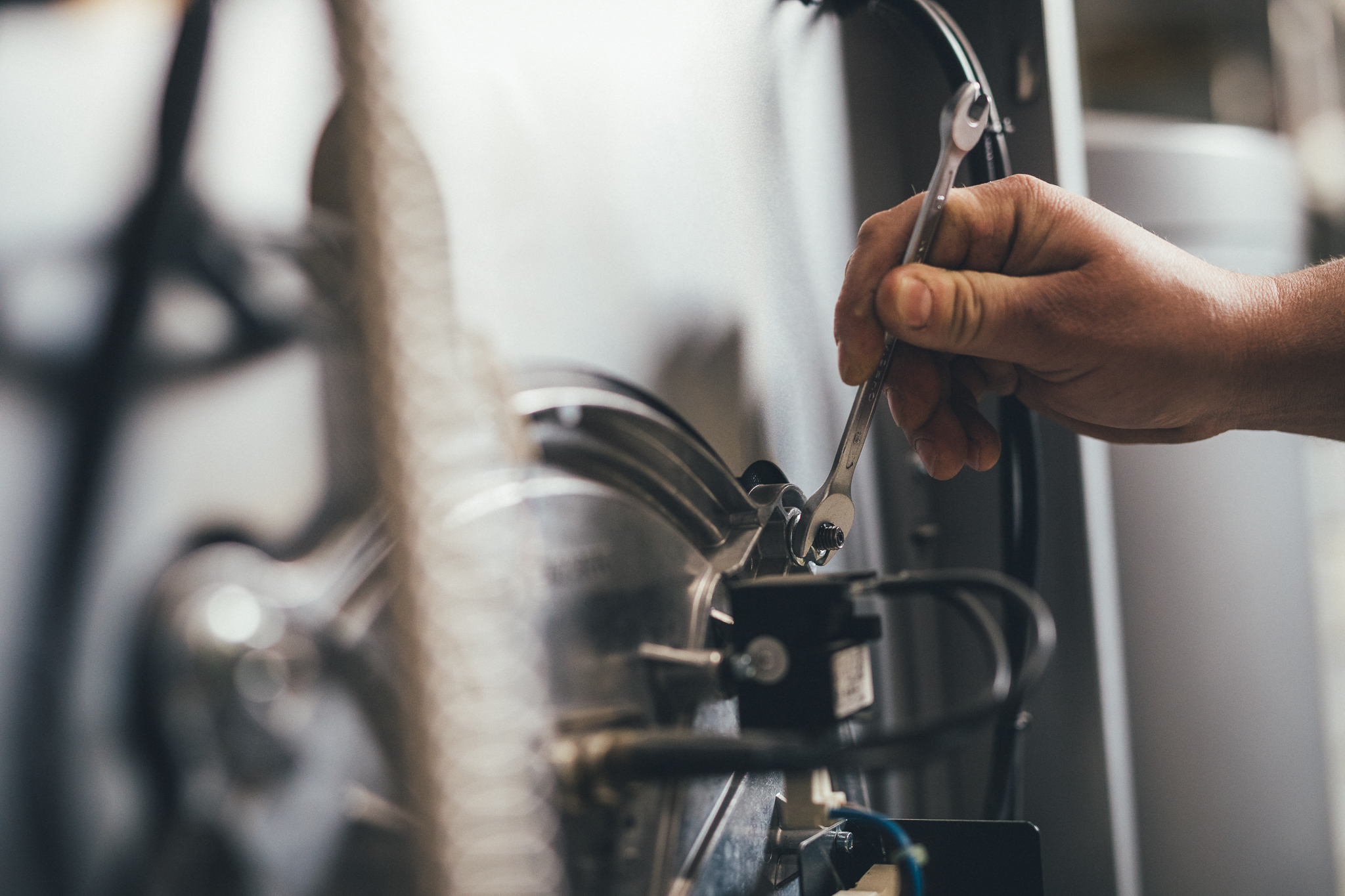 Hand mit Schraubenschlüssel bei Reparatur einer Heizungsanlage