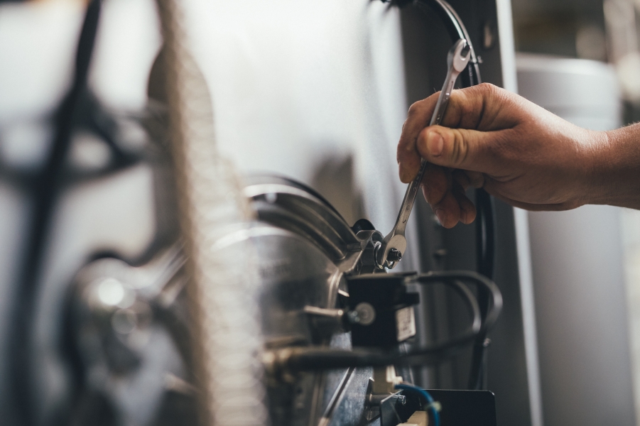 Hand mit Schraubenschlüssel bei Wartung einer Heizungsanlage