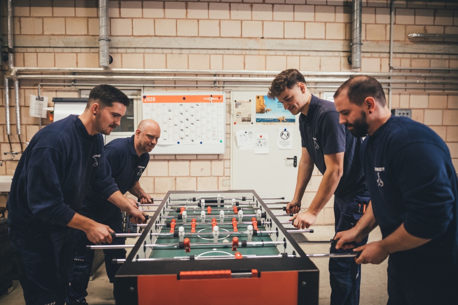 Vier Männer spielen Tischkicker in Werkhalle