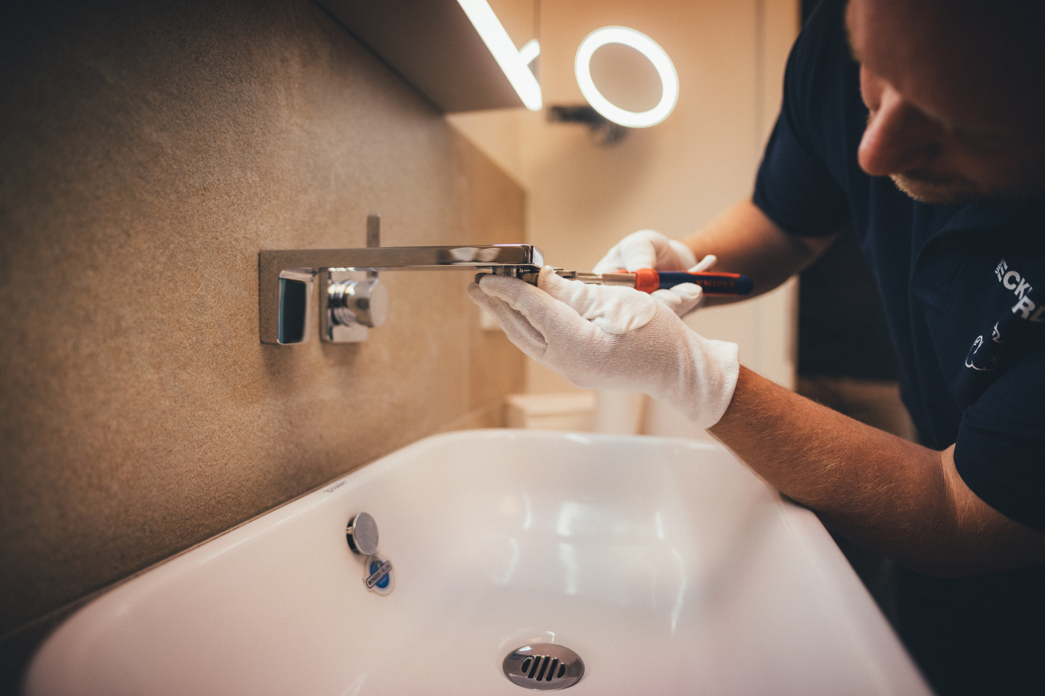 Monteur montiert Waschtischarmatur mit Werkzeug