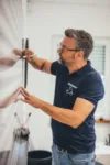 Mann im Eckhardt-Shirt markiert Wand mit einem Stift