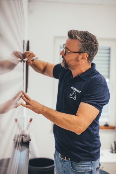 Mann im Eckhardt-Shirt markiert Wand mit einem Stift