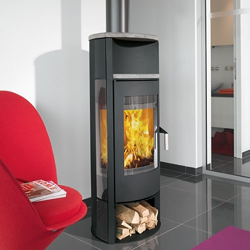 Hoher Kaminofen neben rotem Sessel auf dunklem Fliesenboden