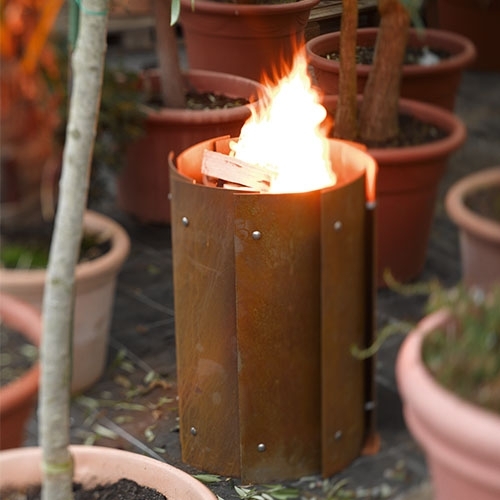 Runde Feuerstelle aus Stahl zwischen Blumentöpfen