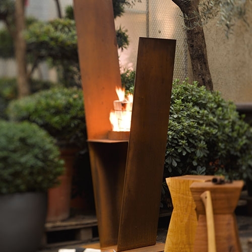 V-förmiger Außenkamin mit Feuer in urbanem Garten