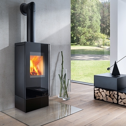 Schwarzer Kaminofen vor Fenster mit Blick ins Grüne