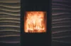 Brennender Kamin mit flackernden Flammen vor Wellenwand