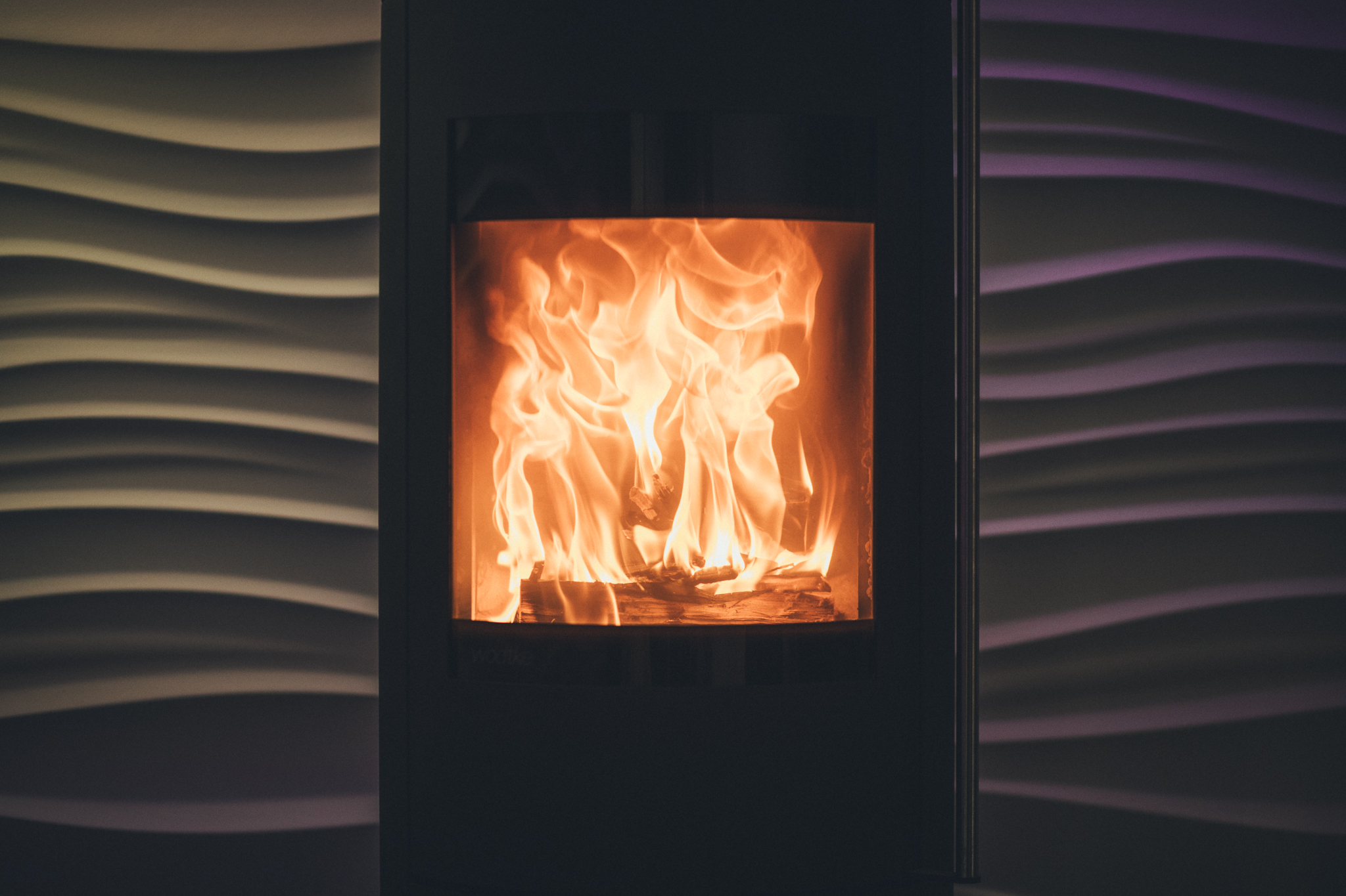 Brennender Kamin mit flackernden Flammen vor Wellenwand