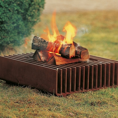 Feuerstelle aus Metall mit Holzscheiten auf Rasenfläche