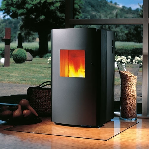 Schwarzer Ofen mit Flamme auf Platte, Glasrohr mit Pellets daneben