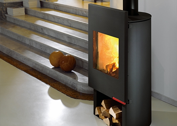 Schwarzer Kaminofen mit sichtbarem Feuer und Holzfach im modernen Raum