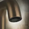 Detailaufnahme eines bronze-matten Wasserhahns vor strukturierter Wand