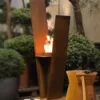 V-förmiger Außenkamin mit Feuer in urbanem Garten