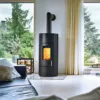 Schwarzer Kaminofen mit Flamme in hellem Wohnzimmer mit Gartenblick