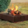 Feuerstelle aus Metall mit Holzscheiten auf Rasenfläche
