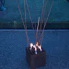 Stahlwürfel mit langen Flammenstäben im Außenbereich bei Dämmerung