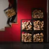 Mann trägt Feuerholz neben Holzregal vor roter Wand
